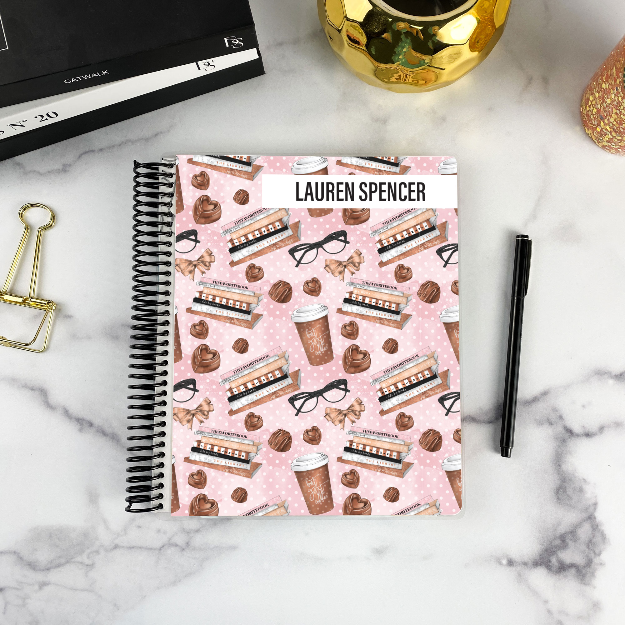 7x9 spiral bound planner in the The Brew Review cover design on a marble surface with styling accessories.