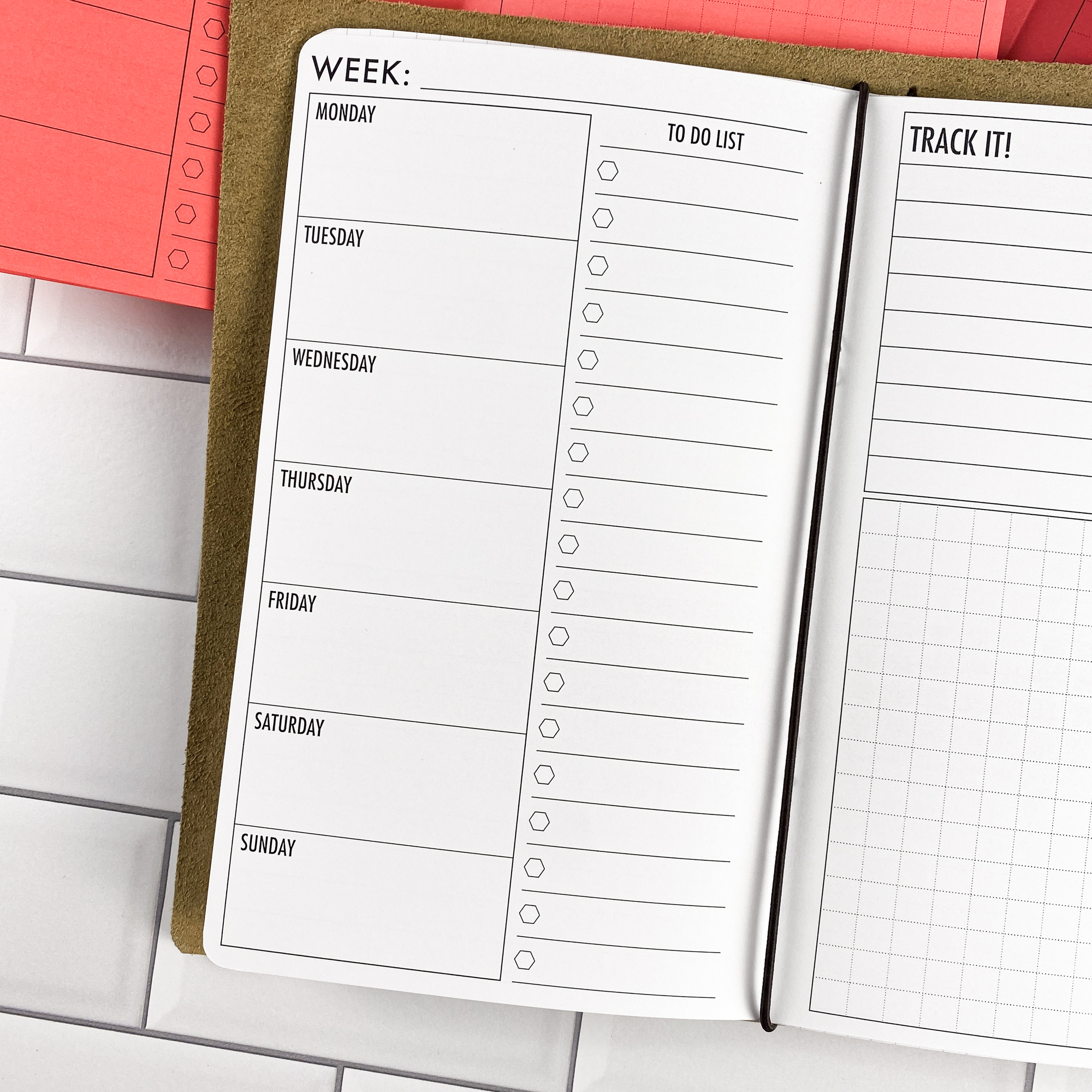 Detail view of the Week at a Glance traveler's notebook refill showing weekly planner spread showing a full week at a glance, displayed with multiple paper color options.