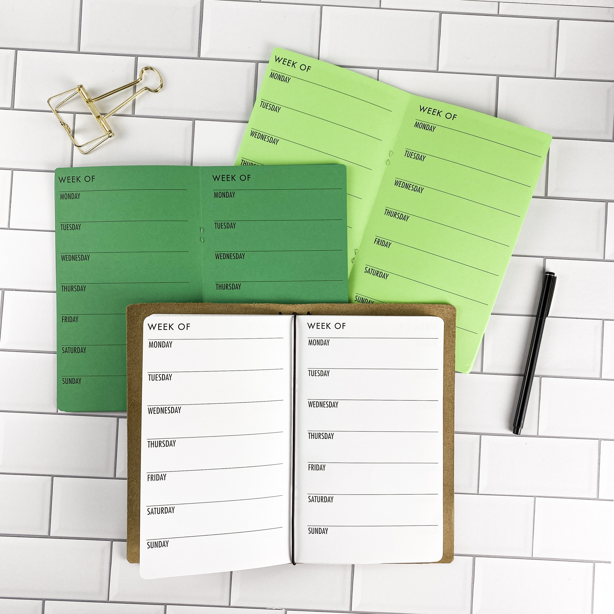 Week on 1 Page Horizontal traveler's notebook refill by CityGirl Planners, showing horizontal weekly planner layout fitting a full week on one page. Three booklets displayed in different paper color options inside a traveler's notebook cover.