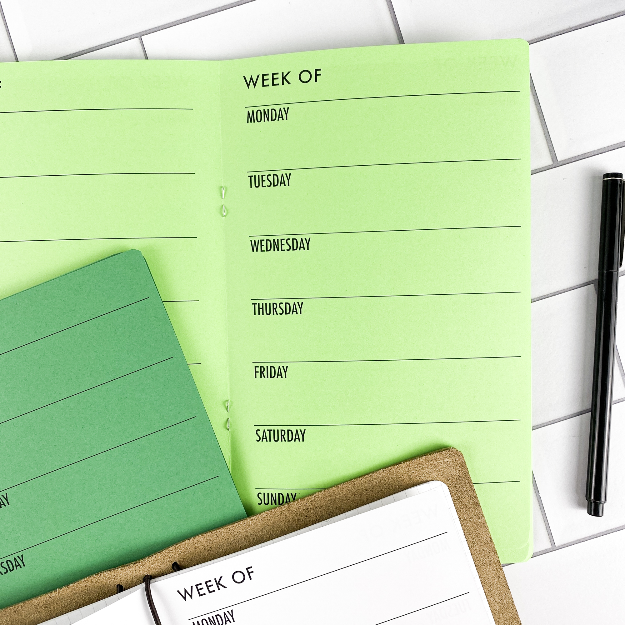 Detail view of the Week on 1 Page Horizontal traveler's notebook refill showing horizontal weekly planner layout fitting a full week on one page, displayed with multiple paper color options.