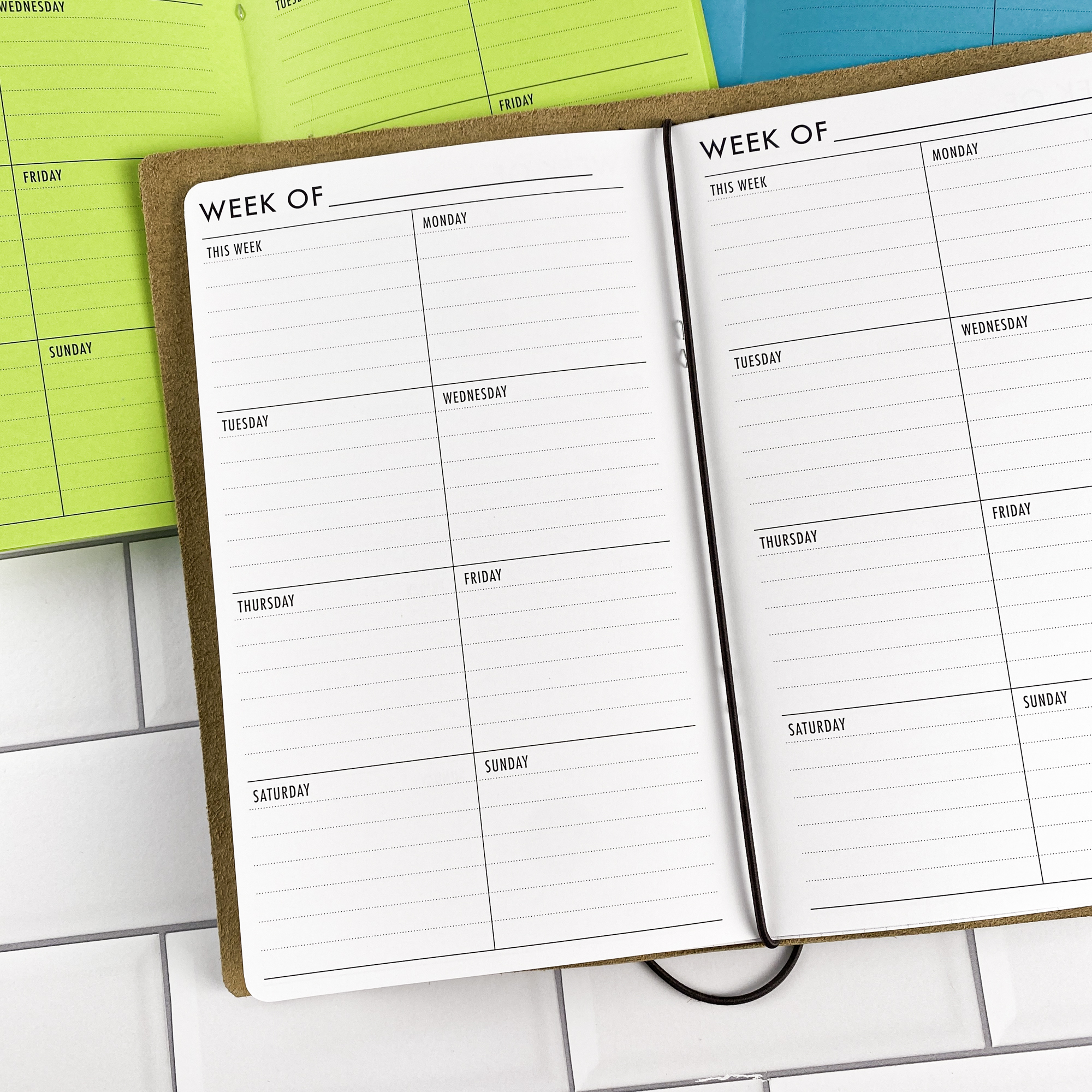 Week on 1 Page Vertical traveler's notebook refill opened to show the vertical weekly planner layout fitting a full week on one page in bright white paper, saddle-stitched booklet format.