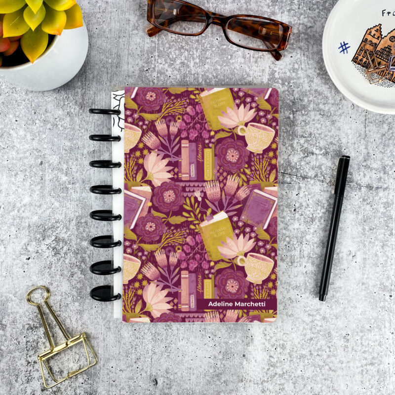 Personalized disc bound password book in purple and green bookish pattern with laminated cover, black discs, and custom name